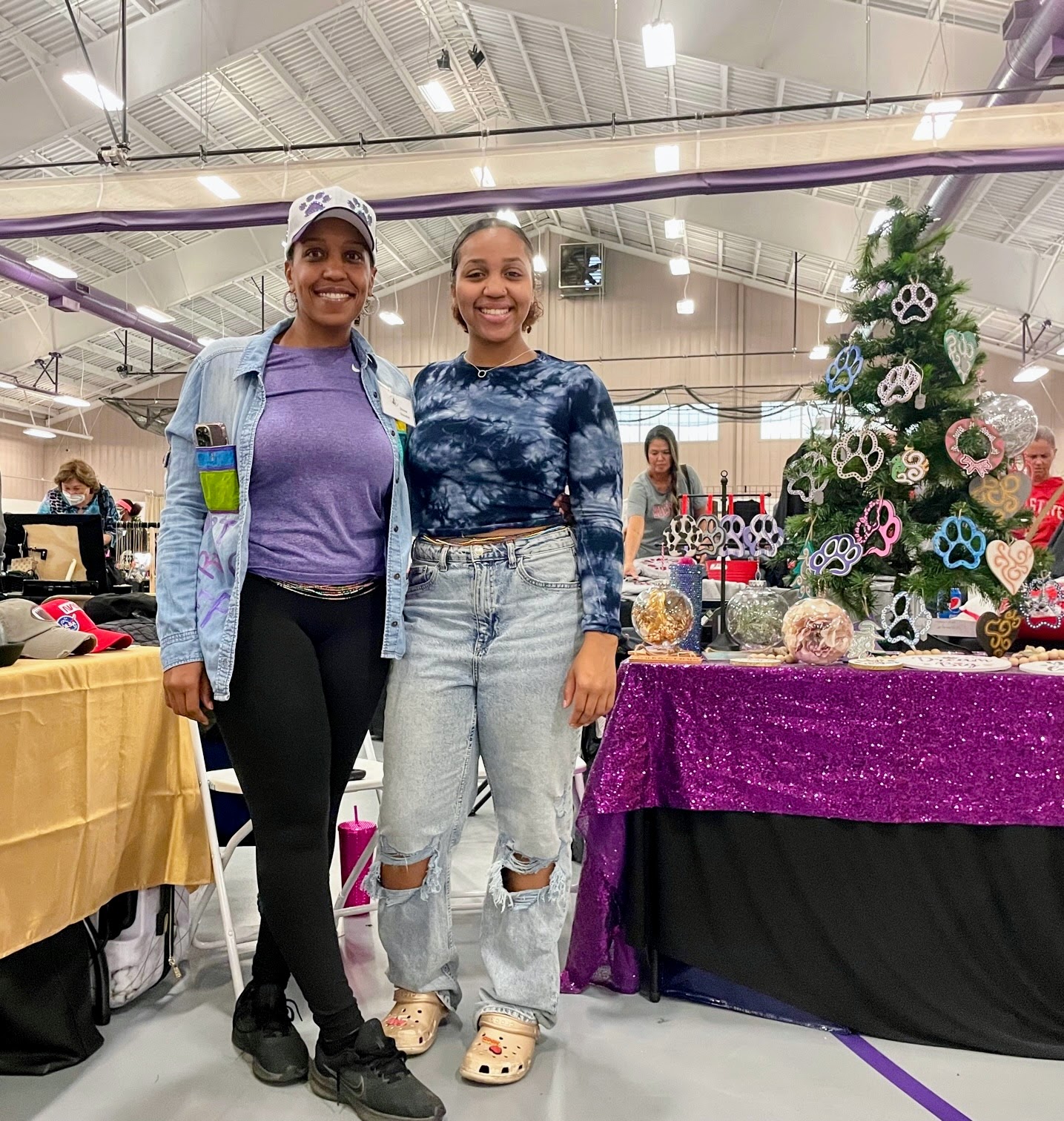 Two women standing in front of a display of ornaments at the PTO Arts & Crafts Fair