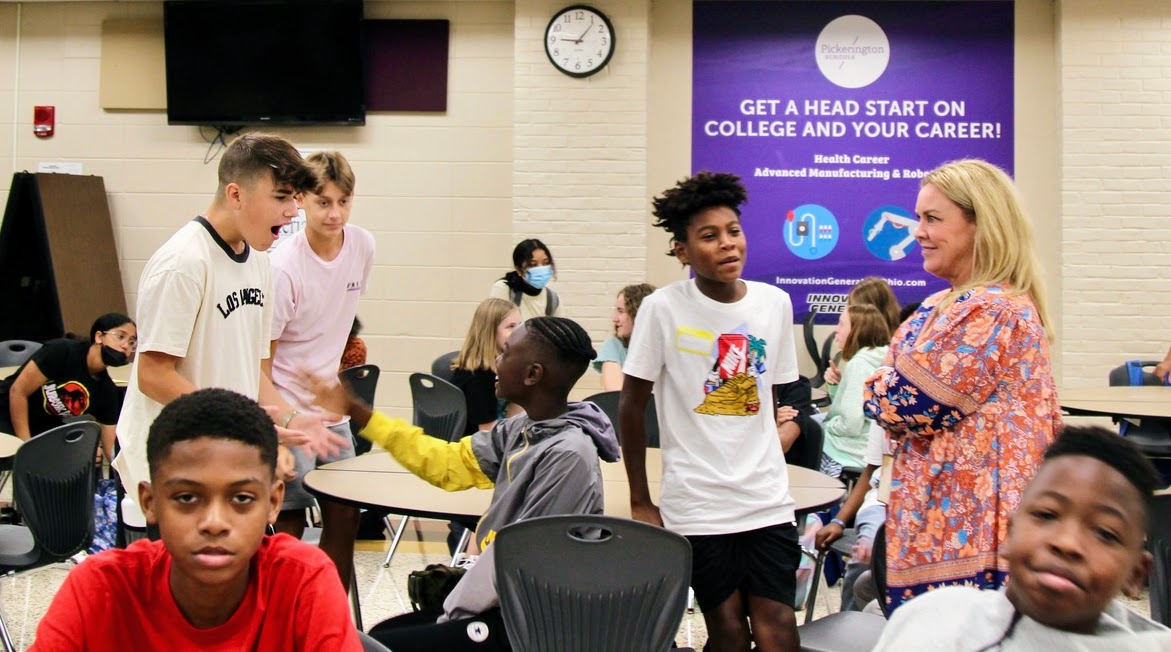 Junior high students interact with a teacher in the school cafeteria