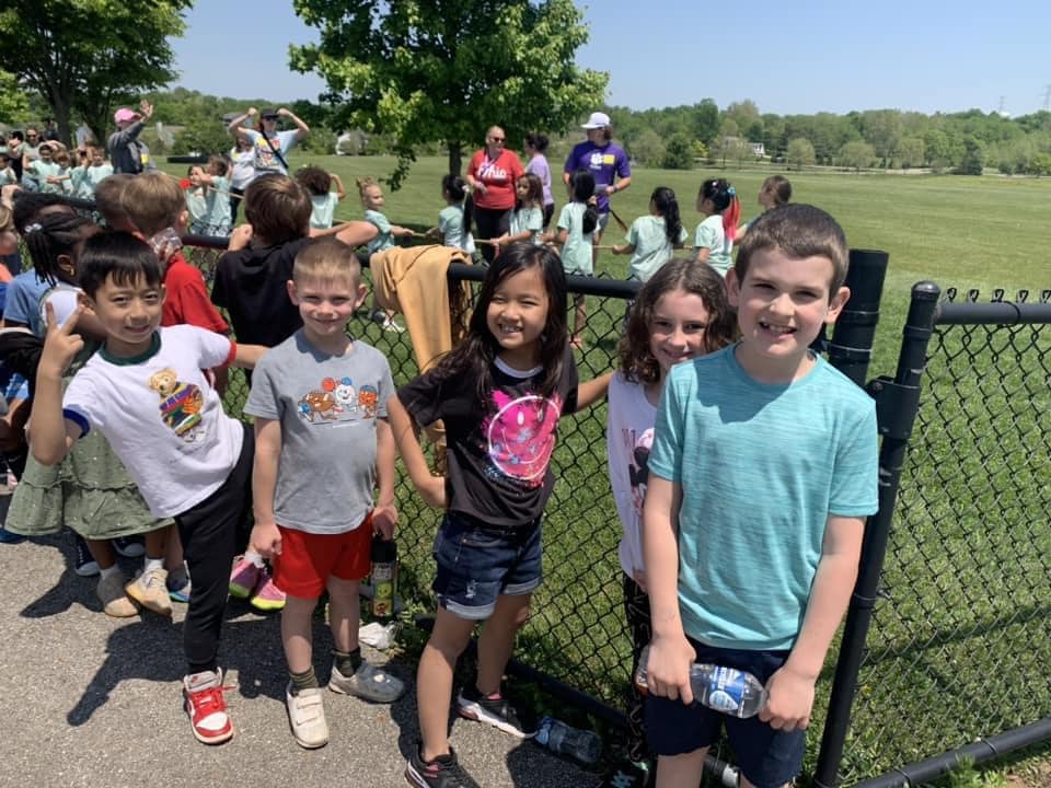 elementary school children lined up and smiling outside in the sun