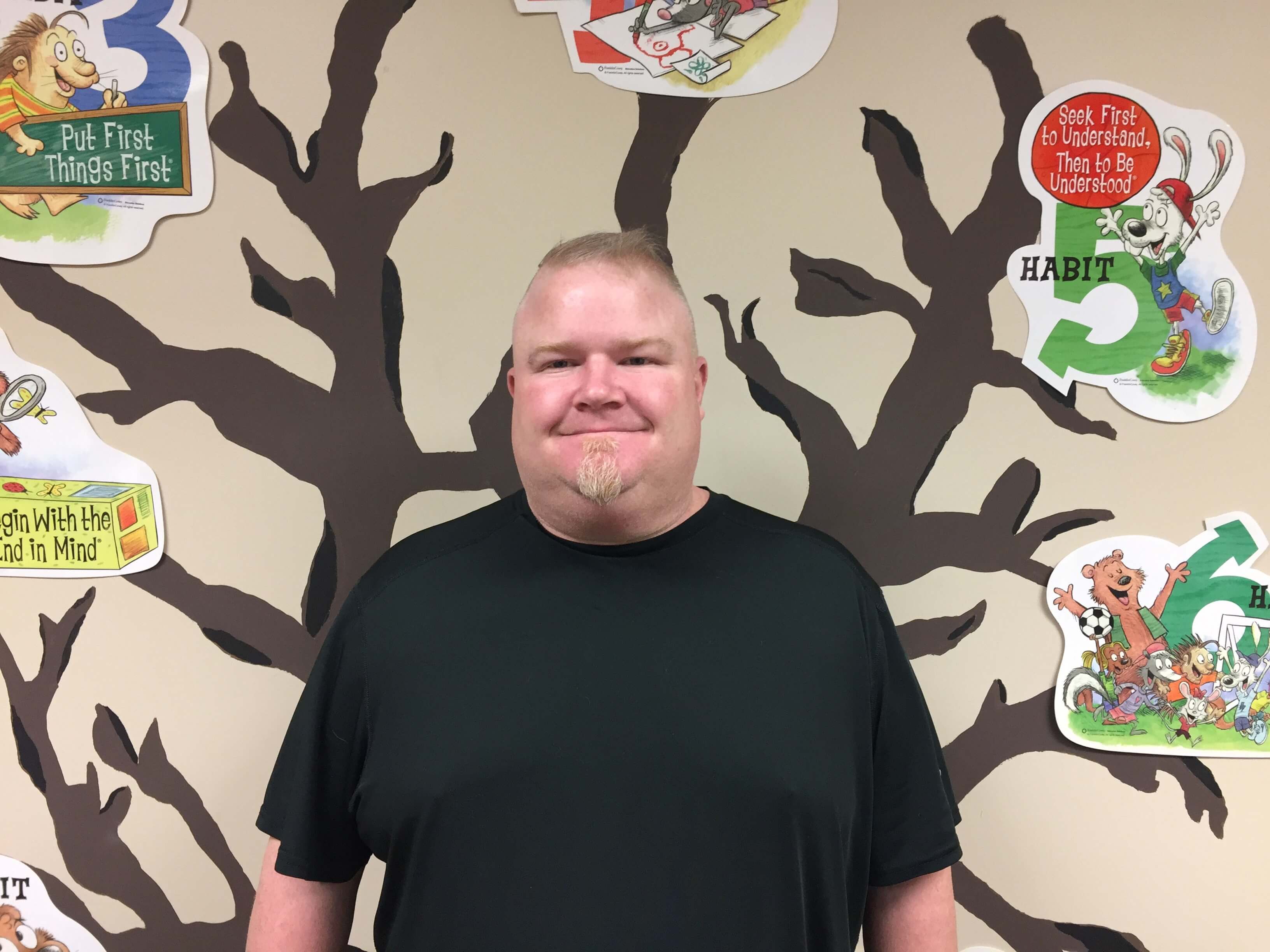 School Counselor Darren Drake standing in front of a tree decorated with the Seven Habits.