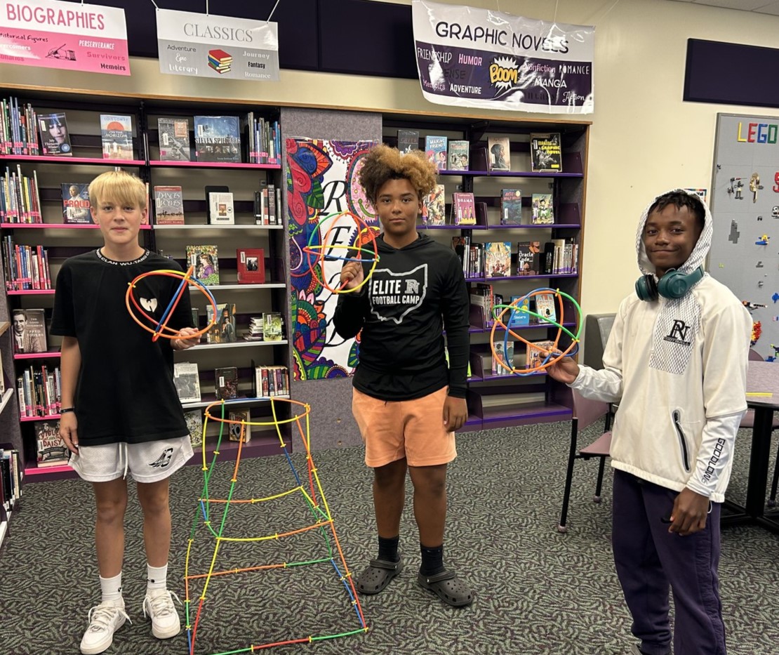 3 students engaged in an activity in the media center