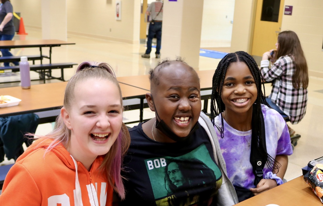 Three middle school girls in a school cafeteria