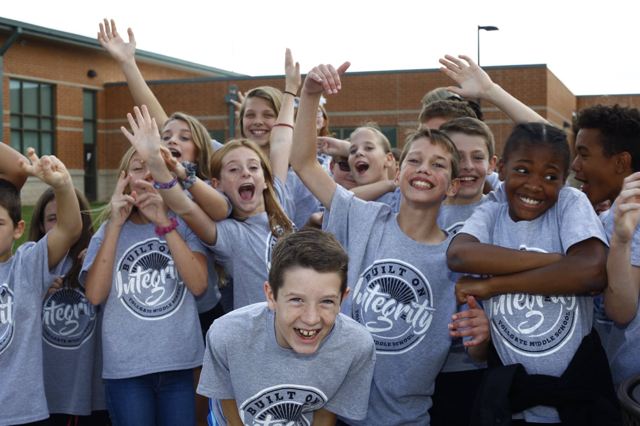 a group of school children wearing t-shirts reading "Built on Integrity"