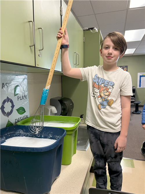 STUDENT WITH LARGE WHISK FOR STIRRING DETERGENT