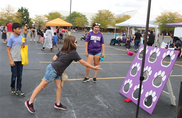 A young attendee tosses a bean bag while playing a children's game.