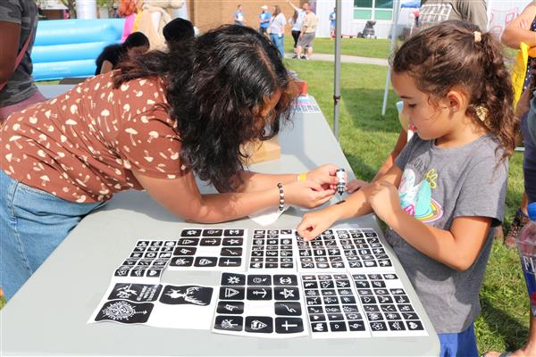A child attending the Family & Community Festival gets a henna tattoo.